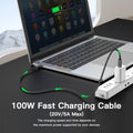 Laptop with a 100W fast charging cable connected to a power strip on a desk.