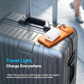A gray hard-shell suitcase on a sidewalk with a white wall charger placed on top of an orange phone case. Text on the image reads 'Travel Light, Charge Everywhere' with a note explaining the product is a wall charger.