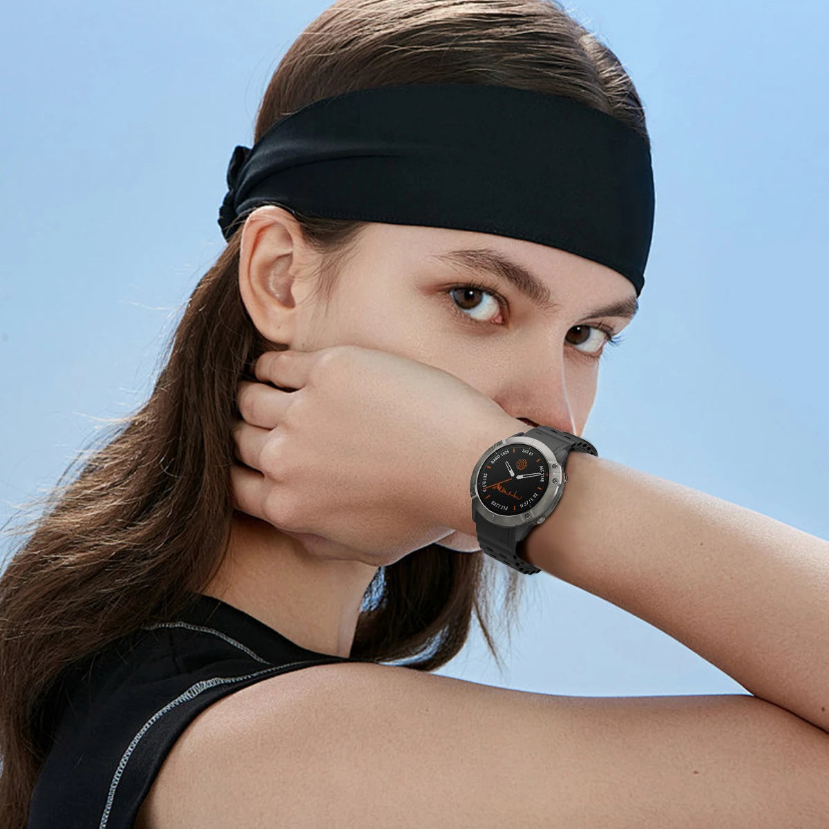 Woman wearing a black headband and smartwatch against a clear blue sky