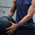 Person holding a medicine ball wearing a smartwatch with a blurred background