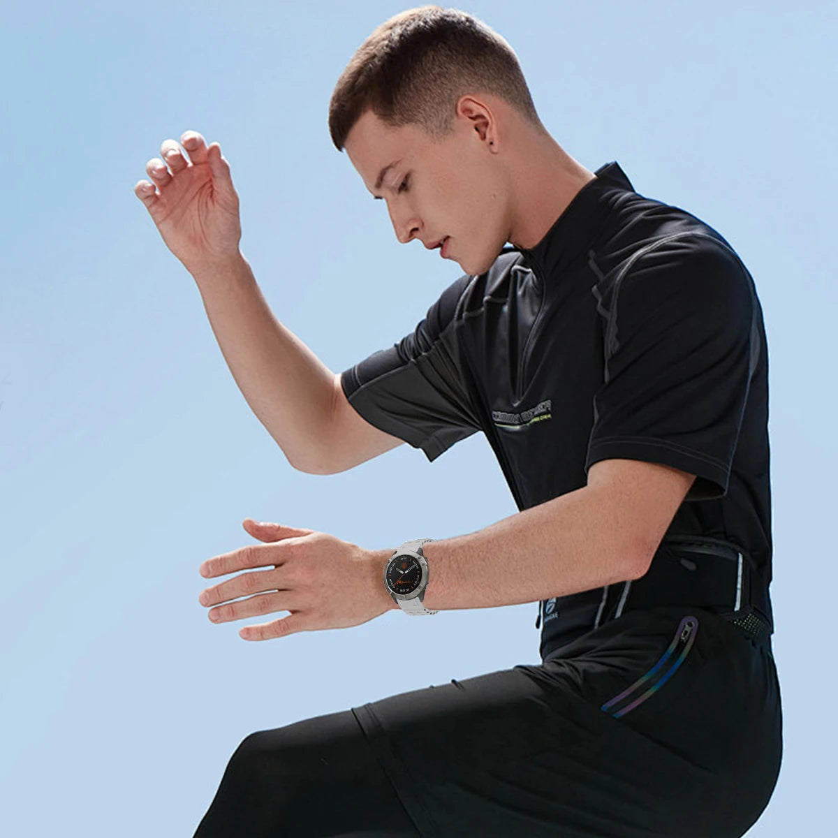Person wearing a black outfit with a watch against a clear blue sky
