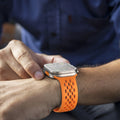 Smartwatch with an orange band on a person's wrist, with a blurred background