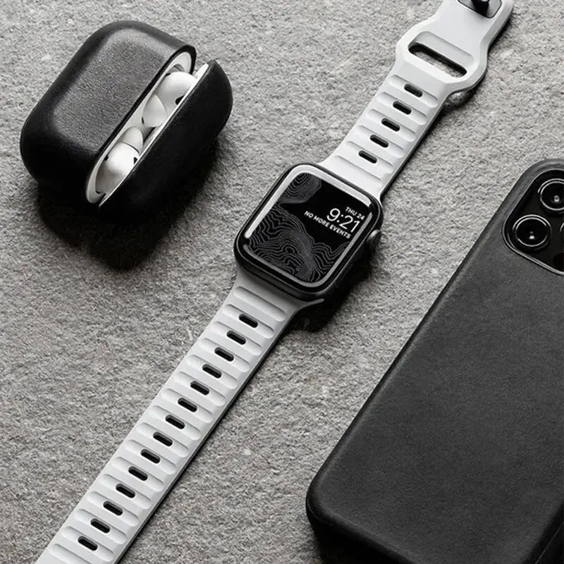 Smartwatch with white band, black case, and phone on a gray surface