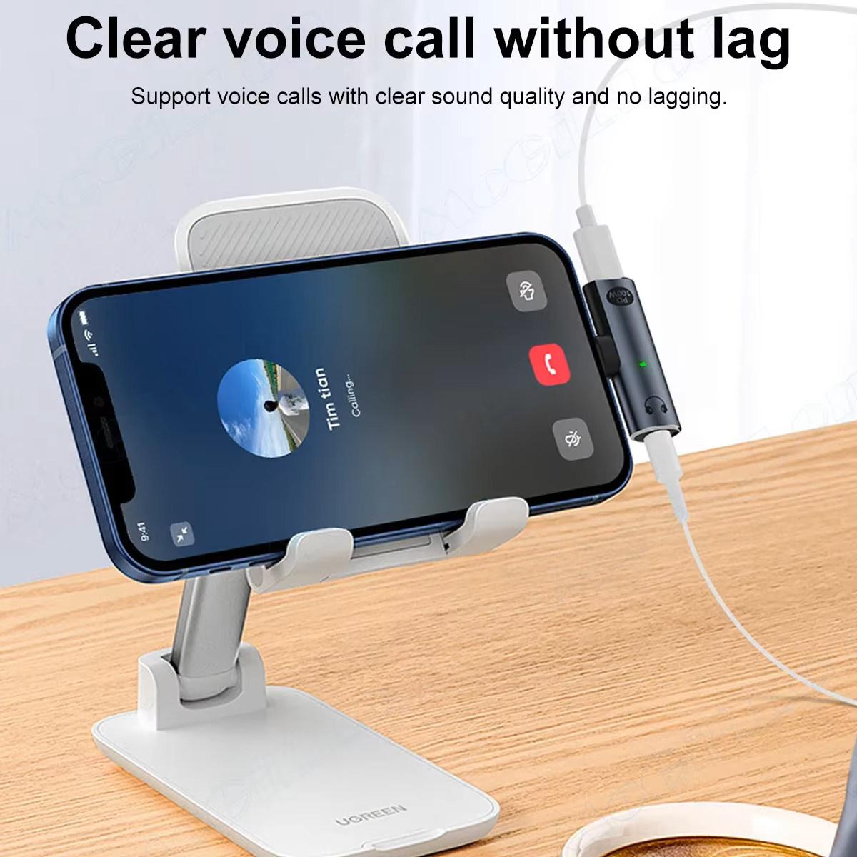 A smartphone resting on a desktop stand during a voice call with an AXYON 2-in-1 USB-C adapter connected, showing simultaneous charging and wired headphone connection.