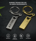 Two keychain USB drives, one silver and one gold, on a dark textured background with text about durability.