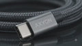 Close-up video of the AXYON Space Grey 100W USB-C to USB-C cable, showcasing its high-density double-woven black and grey braided nylon jacket, sleek laser-etched aluminum alloy connector shell, and flexible structural strain relief boot.