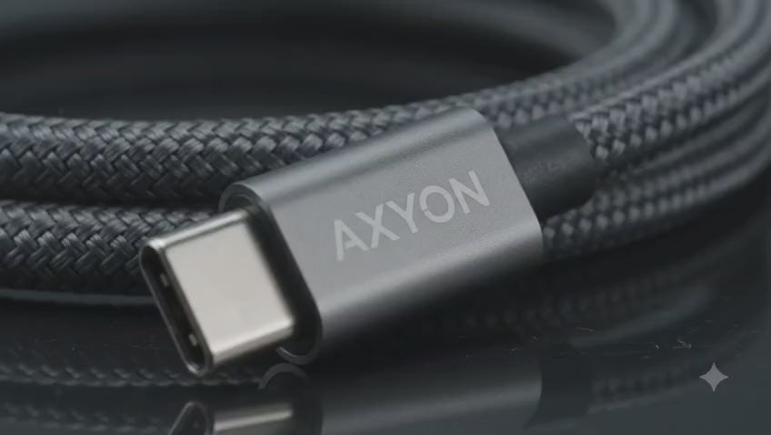 Close-up video of the AXYON Space Grey 100W USB-C to USB-C cable, showcasing its high-density double-woven black and grey braided nylon jacket, sleek laser-etched aluminum alloy connector shell, and flexible structural strain relief boot.